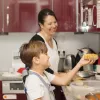 Eine Frau und ein Kind stehen in einer Küche und kochen fröhlich